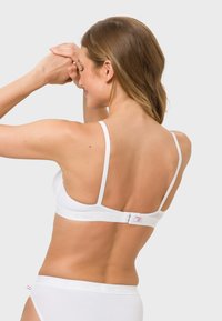 White, lightweight bra with adjustable straps and a hook-and-eye closure. Smooth fabric with subtle brand logo along the band.