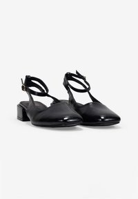Chaussures noires à bride arrière avec un bout pointu, en cuir brillant, avec des brides de cheville et un petit talon carré. Design simple avec peu de matériel.