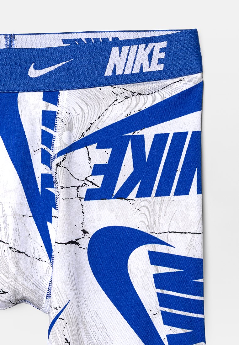 Niebiesko-biała tkanina w wzory z wyraźnym logo Nike, prezentująca nowoczesny design o teksturowanym wyglądzie.