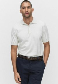 Lichtgrijs polohemd met korte mouwen en een zachte textuur, voorzien van een kraag en drie knopen, gecombineerd met marineblauwe broek en een bruin gevlochten riem.