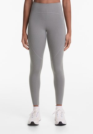Gray high-waisted leggings with a smooth texture, featuring contrasting seam details and a fitted design. Paired with light athletic shoes.