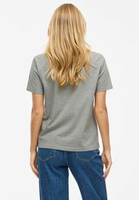 T-shirt en coton gris à manches courtes, col rond et coupe décontractée, associé à un jean en denim bleu taille haute, montrant une vue de dos.
