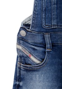 Ogrodniczki dżinsowe mają wyblakły niebieski kolor, regulowane ramiączka, metalowy guzik i małą metkę z logo przy kieszeni.