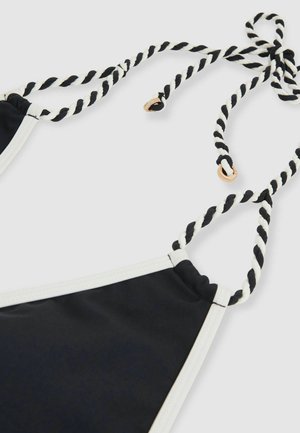 Schwarzer Bikini-Oberteil mit weißem Saum, ausgestattet mit verdrehten schwarz-weißen Trägern und goldenen Hardware-Akzenten. Glatte Stoffoberfläche.