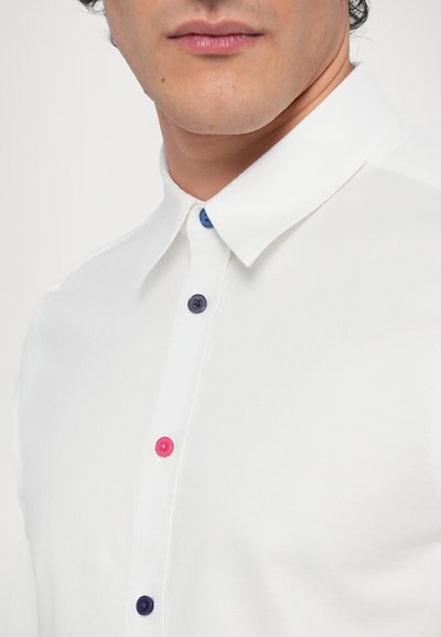 Camicia bianca con collo e bottoni colorati: rosa, blu e viola. Tessuto liscio con un design classico. Primo piano del collo e della patta dei bottoni.