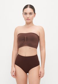 Haut de bikini bandeau marron avec un centre froncé, associé à un bas taille haute. Tissu lisse et extensible avec une finition mate.