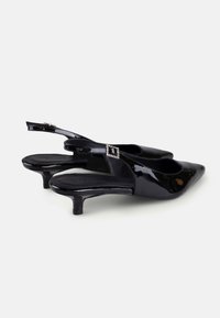 Cizme negre din patent, cu toc slingback, vârf ascuțit, toc mic și un detaliu decorativ cu o cataramă cristalină pe curea. Suprafață netedă și lucioasă.