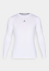 Hvid langærmet tætsiddende atletisk skjorte med rund halsudskæring og et lille sort Jumpman-logo centreret på brystet.