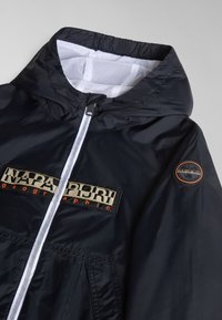 Svart jacka med en nätfoder huva. Har full dragkedja, framfickor och en broderad logotyp på bröstet och ärmen. Slät yta.