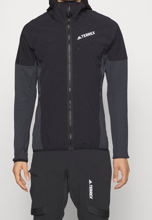 Giacca Terrex nera con zip frontale, maniche testurizzate, cappuccio regolabile e dettagli con logo. Presenta polsini elasticizzati e tasche laterali.