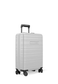 Valise de cabine rigide en argent avec des rainures verticales, poignée télescopique, quatre roues noires et une poignée latérale.