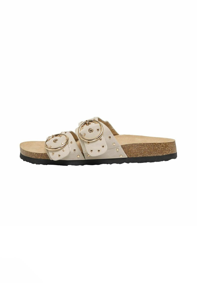 Sandali con fibbia, dotati di due ampie cinghie beige, elementi di hardware circolari in oro e dettagli con borchie, su una soletta in sughero e suola in gomma nera.