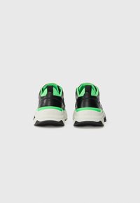 Zwarte en groene sneakers met een mesh bovenwerk en rubberen zool. Heeft een gevoerde kraag en contrasterende hielaccents.