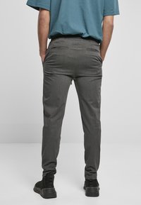 Pantalones gris ajustados con una textura suave, cinturilla elástica y dos bolsillos traseros, combinados con una camiseta azul de corte relajado y botas negras.