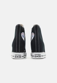 Sneakers alte nere in tela con suole in gomma bianche, dotati di toppe con il logo Converse All Star e cuciture bianche a contrasto.
