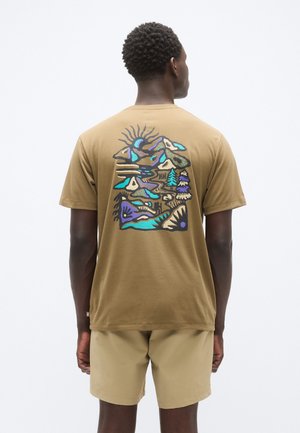 Barna pamut póló színes grafikai mintával a hegységekről, napról és fákról a hátoldalon. Egyszerű kialakítás, rövid ujjú, laza szabás.