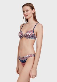 Set di reggiseno e bikini con motivo floreale in navy, rosso e bianco. Il reggiseno presenta spalline regolabili e supporto con stecche.
