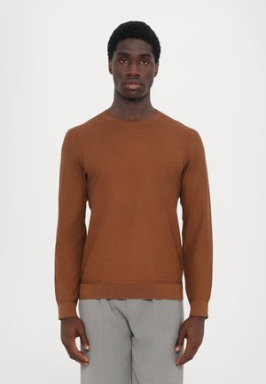 Brown round-neck sweater with long sleeves, made of textured knit fabric. Paired with light gray tailored trousers.
