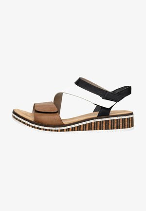 Sandale en cuir marron et blanc avec une large sangle, velcro ajustable, et une semelle plateforme rayée en liège et en caoutchouc.