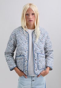 Chaqueta acolchada en azul claro con un estampado de leopardo, con ribetes en azul marino, dos bolsillos frontales y botones a presión plateados.