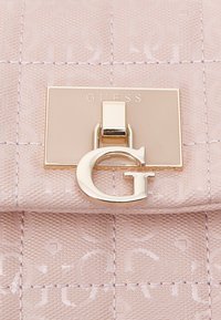 Różowa pikowana torebka na ramię z zapięciem ze złotym okuciem i wyraźnym złotym logo "G". Teksturowana powierzchnia z delikatnymi geometrycznymi wzorami.