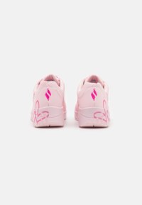 Rosa träningsskor med en slät läderöverdel, med mörkare rosa accenter och en blommig design på sidorna. Strukturerade gummisulor.