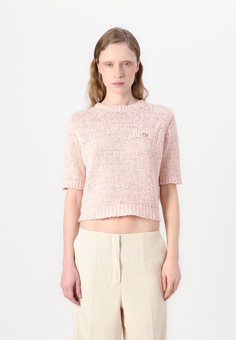 Top rose en tricot à manches courtes avec une finition texturée, col rond et une petite poche dotée d'un accent décoratif. Design court.