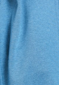 Lichtblauwe stof met een gestructureerd weefpatroon, met een subtiele glans. Het materiaal ziet er zacht en glad uit, met zachte plooien.