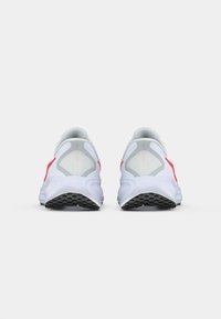 Λευκά αθλητικά παπούτσια με κόκκινες λεπτομέρειες, διαθέτουν δικτυωτό πάνω μέρος, επενδυμένο κολάρο και υφασμάτινη σόλα για πρόσφυση. Εμφανίζεται η πίσω όψη.