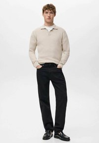 Beige geribbelde gebreide trui met kraag, gecombineerd met zwarte broek met rechte pijpen en zwarte loafers. Eenvoudig design, zachte textuur.