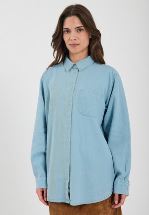 Svetlomodrá džínová košeľa na gombíky s golierom, dlhými rukávmi a jednou náprsní kapse. Obsahuje subtílnu textúru a plastové gombíky.