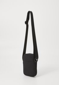 Svart crossbody bag med rektangulær form, laget av myk stoff, med justerbar stropp og minimalistisk design.