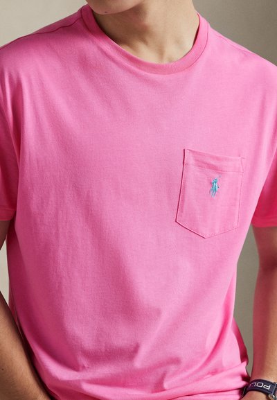 Ροζ βαμβακερό T-shirt με στρογγυλή λαιμόκοψη και κοντά μανίκια, με τσέπη στο αριστερό στήθος και μικρό μπλε κεντημένο λογότυπο.