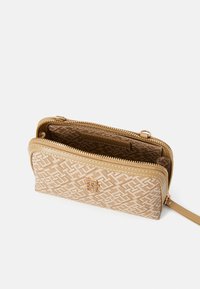 Portofel crem cu fermoar, cu un model geometric țesut, accesorii aurii și mai multe compartimente interioare pentru carduri și bancnote.