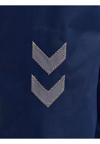 Marinfärgad tyg har två grå broderade chevronformer, var och en med zickzackstygning längs kanterna, vilket skapar en texturerad detalj.
