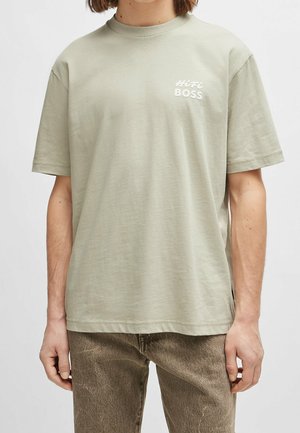 Lichtgroen katoenen T-shirt met korte mouwen, ronde hals en de tekst "HiFi BOSS" in het wit op het linkerborstgebied. Eenvoudig ontwerp.