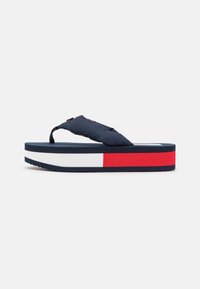 Navy flip-flop sandal with a padded strap, featuring a thick, layered sole in navy, white, and a red accent stripe. Textured, non-slip bottom.