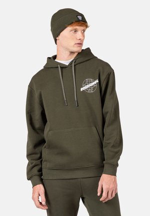 Felpa verde oliva realizzata in misto cotone con tasca frontale, cappuccio con cordino e grafica del logo bianco. Abbinata a pantaloni coordinati.
