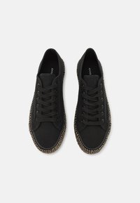 Sneakers neri in tela con punta rotonda, design con lacci e bordo intrecciato e testurizzato attorno alla suola. Etichetta visibile all'interno della scarpa.