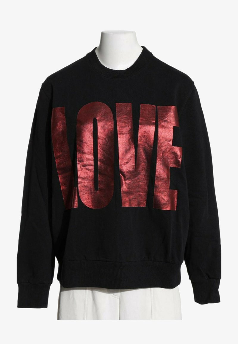 Sweat-shirt noir à manches longues avec de grandes lettres rouges métalliques formant le mot LOVE sur la poitrine, présenté sur un torse de mannequin blanc.
