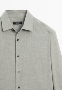 Lichtgrijze lange mouwen shirt met een kraag, gemaakt van textuurstof, met donkere knopen en een label met de tekst "Massimo Dutti."