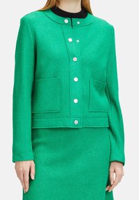 Grön ullblandad jacka med rundad krage, framknappar, två påsydda fickor och texturerad yta. Slät tyg och figursydd design.