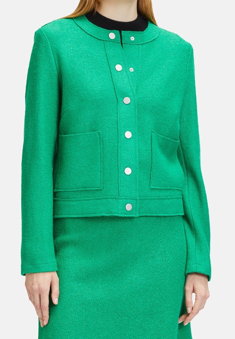 Grön ullblandad jacka med rundad krage, framknappar, två påsydda fickor och texturerad yta. Slät tyg och figursydd design.