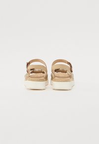 Tan sandalen met dubbele verstelbare banden, geweven details op de zool en een textuur voetbed; lichtgewicht en platform ontwerp.