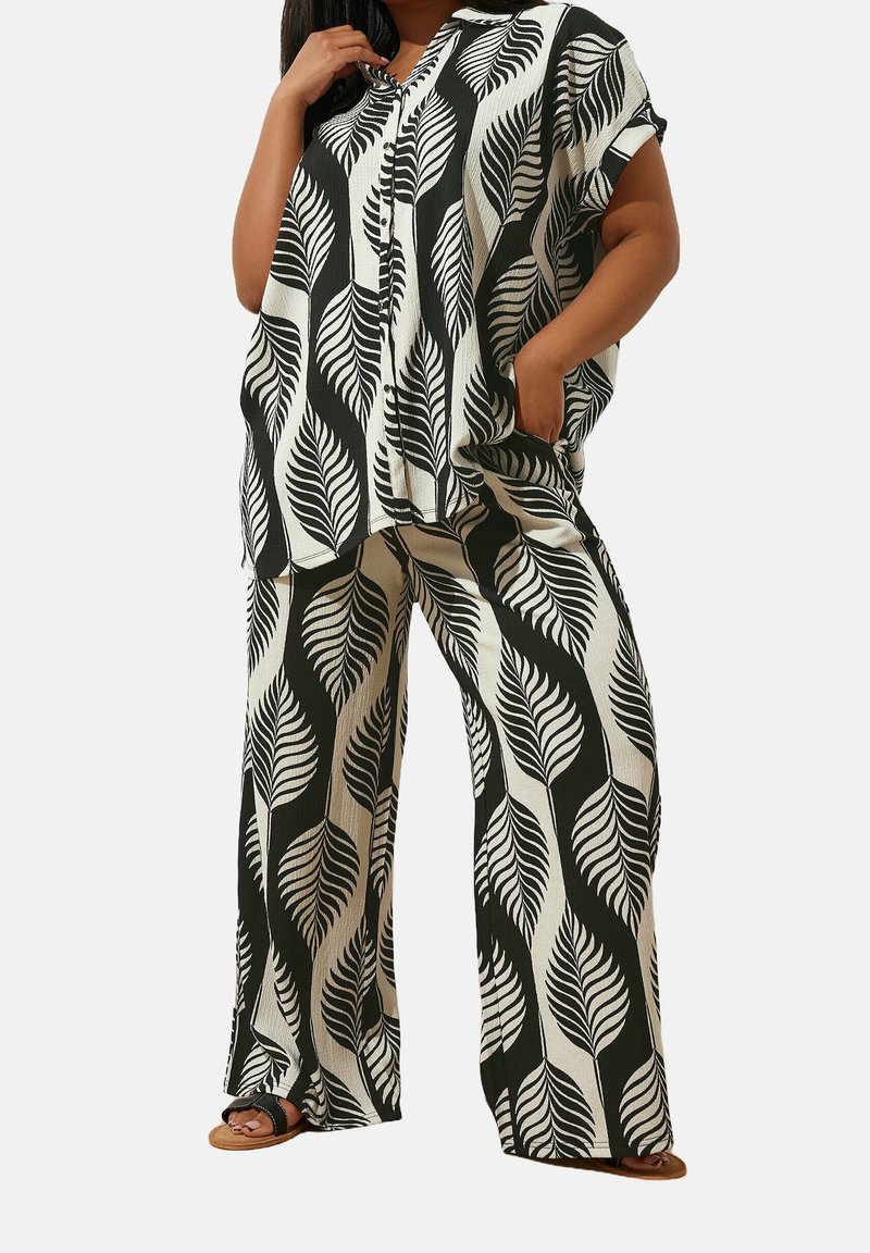Outfit a fantasia di foglie in bianco e nero con una maglietta morbida dotata di un'apertura con bottoni e pantaloni a gamba larga. Tessuto texturizzato, vestibilità rilassata.