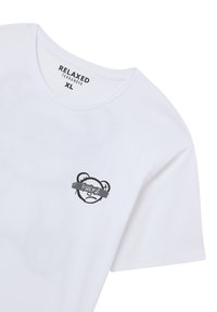 T-shirt bianco a maniche corte con scollatura rotonda, caratterizzato da una grafica di un orso nero e dalla parola "RULES" su un nastro grigio.