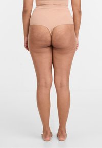 Hautfarbene, hochgeschnittene Panties mit glatter Textur, die ein minimalistisches Design und eine vollflächige Rückseite zeigen. Weicher Stoff ohne sichtbare Muster.