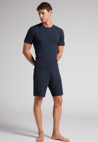 Marineblaues Baumwoll-T-Shirt mit kurzen Ärmeln, kombiniert mit passenden Shorts. Das T-Shirt hat einen Rundhalsausschnitt; die Shorts verfügen über einen elastischen Bund.