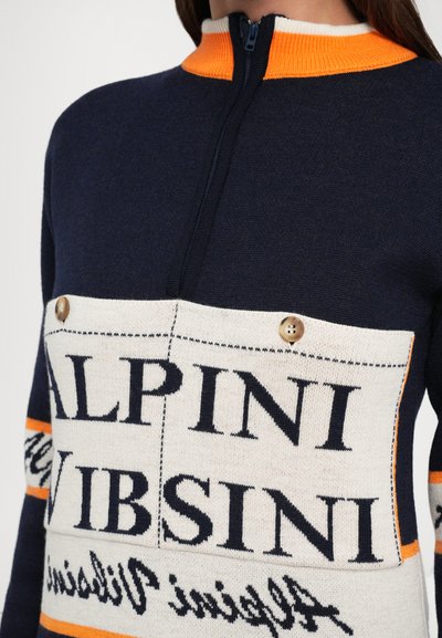 Mornarsko modra zip-up svetilka z oranžnim ovratnikom ter velikim belim panelom, ki ima črne napise in gumbe na prsih.