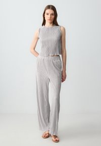 Grijs geplooid twee-delig outfit bestaande uit een mouwloze cropped top en losse broek, beiden met verticale strepen en een zachte, lichte textuur.